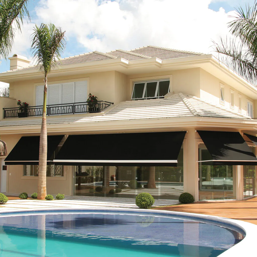 Toldo de braços retráteis Copato para sombra com estilo em fachada com grandes aberturas envidraçadas