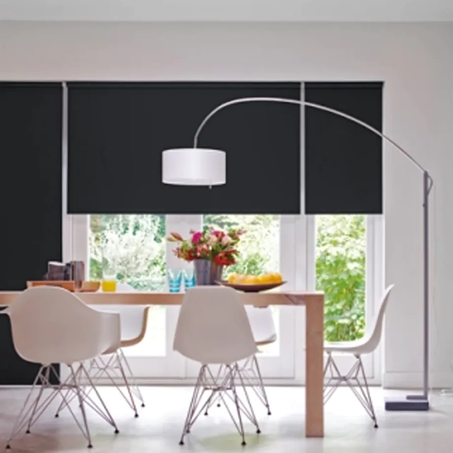 Cortinas rolô blackout pretas sob medida da Copato instaladas em sala de jantar com iluminação natural